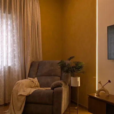 A cozy reading corner in a master bedroom, featuring a comfortable recliner and warm ambient lighting from a vertical LED strip.