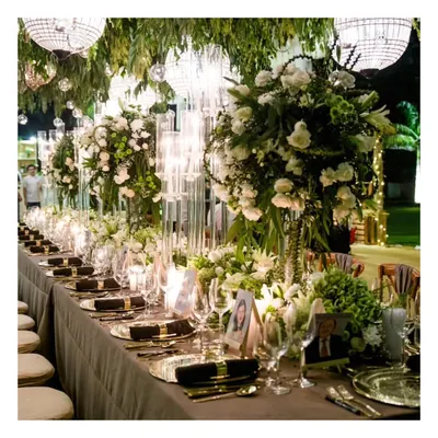 A breathtaking view of a grand sit down dinner arrangement, with lush greenery and sparkling chandeliers hanging overhead. This setup showcases our ability to integrate our catering service with large scale, opulent decor for a truly immersive wedding experience.