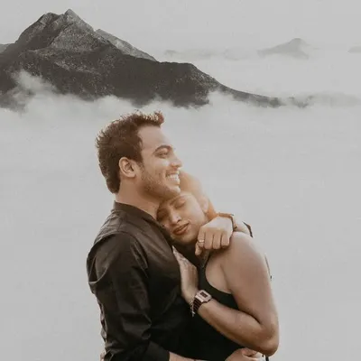 Above a sea of clouds on a misty mountain, this couple's embrace feels like the only thing in the world. This black and white portrait focuses purely on the serene, powerful emotion of their bond during their outdoor couple photoshoot.