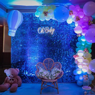 Modern, chic, and totally Instagrammable. This "Oh Baby" setup features a sparkling blue sequin wall, a trendy neon sign, and a gorgeous peacock chair, making the mom-to-be feel like a true queen on her special day.