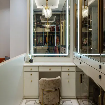 This is the epitome of closet goals. A dedicated vanity with a large, backlit mirror is perfectly integrated into this luxurious walk-in closet, complete with a plush stool and ample drawer space.