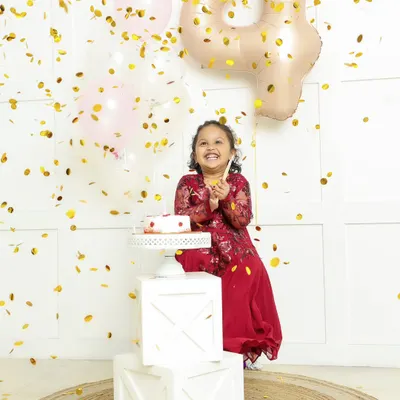 Pure birthday joy. This little girl is showered in golden confetti as she celebrates turning four, her happy laugh lighting up the room.