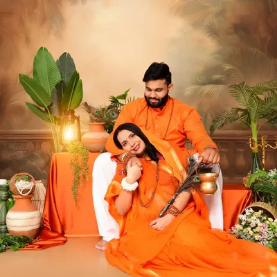 A beautiful couple's portrait from our Ram and Sita inspired maternity shoot. The couple is dressed in traditional orange attire, sharing a tender moment in a setting designed to evoke a classic, epic feel.