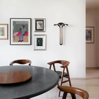 A closer look at the art-filled dining space in our Collectors House. The custom terrazzo and teak dining table is surrounded by classic chairs, with a gallery wall and a unique sculptural piece adding layers of personality.