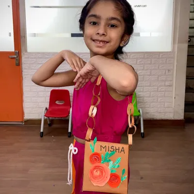 This student is striking a pose with the stylish paper purse she made. This craft project teaches kids about construction, decoration, and creating something functional from simple materials.