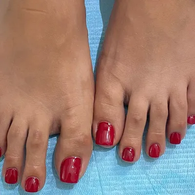 A clean and classic pedicure service. This image shows perfectly shaped toe nail extensions with a vibrant red gel polish, proving that attention to detail extends to your feet too.