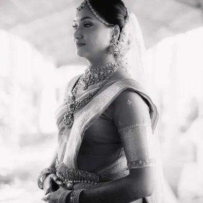 A stunning black and white portrait of the bride, Mohita. Her thoughtful expression and the beautiful details of her South Indian bridal attire are captured in soft, natural light.