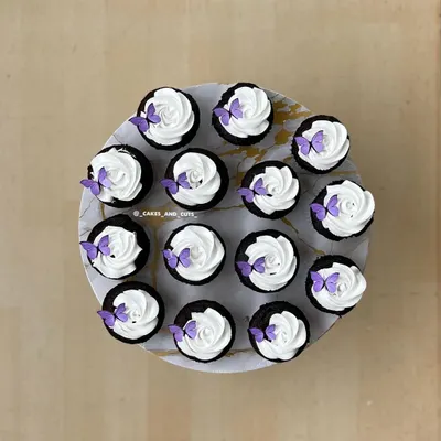 A top-down view of our popular butterfly cupcakes, with delicate purple butterflies on swirls of white frosting.