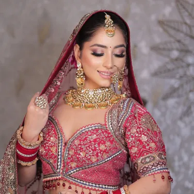 A close-up of this beautiful bride, showcasing the soft glam eye makeup and flawless base that complements her traditional red lehenga. Her smile says it all.