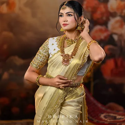 A model looking regal in a classic off-white and gold Kanjeevaram saree. The look is completed with a heavily embroidered blouse and traditional temple jewellery, perfect for a South Indian bride.
