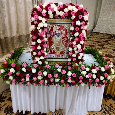 We create beautiful floral frames for deities to make your home pooja special. Here, a portrait of Shrinathji is adorned with a dense arch of fresh roses, creating a sacred and beautiful focal point for prayers.