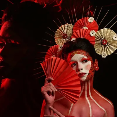 Another angle from our Geisha-inspired creative shoot. The use of dramatic red lighting and shadows adds depth and mystery to the portrait, highlighting the intricate makeup and headpiece.
