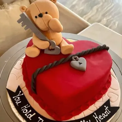 This heart-shaped Valentine's cake sends a clear message with a charming teddy bear holding the "key to my heart." The detailed fondant work makes it a memorable romantic gesture.