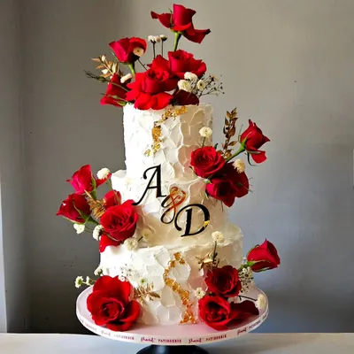 A truly mesmerizing engagement cake. The combination of rustic, textured ivory whipped cream and bold, fresh red roses creates a dramatic and romantic centerpiece. The gold leaf accents add a final touch of luxury.