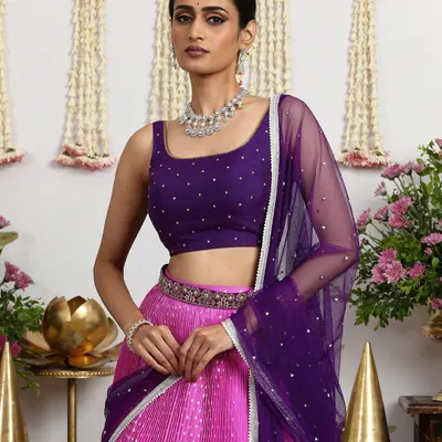 A fusion of tradition and modernity, this hot pink and deep purple Bandhani lehenga is a trousseau essential. The rich purple silk brocade border adds a touch of Banarasi elegance.