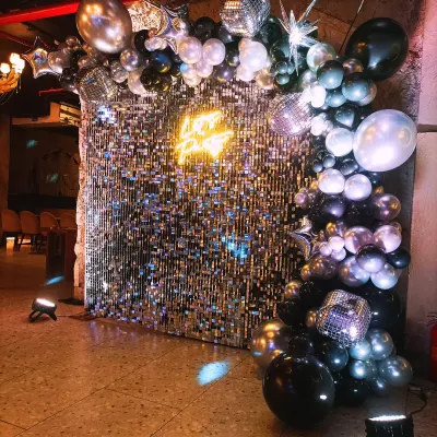 This is one of our favourite setups for a high-energy corporate party. The combination of a shimmer wall, a cool neon sign, and a stylish balloon garland creates a fantastic focal point for any event. 🤩