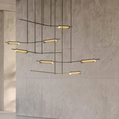 The Volant chandelier by Ross Gardam, a kinetic sculpture of brass bars and tubular glass, creates an elegant equilibrium in this concrete-walled space. Its form gives the impression of objects in motion, providing a captivating yet soothing focal point.