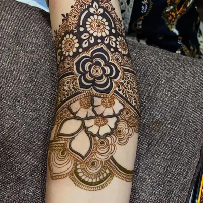 This design features a large, bold flower as the centerpiece on the forearm, surrounded by delicate shading and smaller floral details. It's a great example of a modern floral cuff.