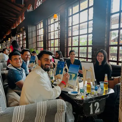 A happy group of friends enjoying a sip and paint session. The combination of a relaxed cafe atmosphere, drinks, and creativity is a perfect recipe for a great time.