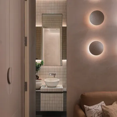 A peek into an ensuite bathroom that continues the story of the guest room. Minimalist tiles, a sculptural vessel sink, and a touch of greenery soften the modern lines and create a cohesive design experience.