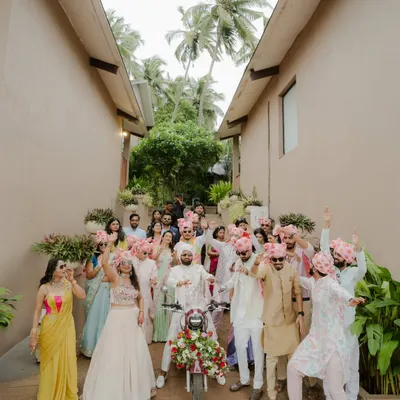 The groom's grand Baraat entry on a decorated Bullet, surrounded by his cheering friends and family. This shot is all about capturing the high energy, swagger, and celebratory chaos of the groom's procession.