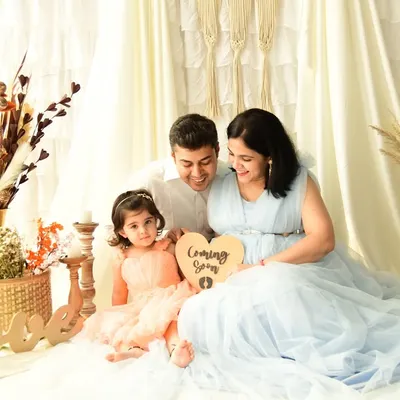 A beautiful family portrait celebrating a new arrival. The whole family is gathered together, holding a "Coming Soon" sign, capturing the shared joy and anticipation.
