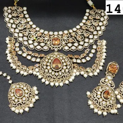 A magnificent bridal choker set made with uncut kundan and polki stones, featuring warm, amber-colored center stones. The set includes a multi-layered necklace, matching earrings, and a maang tikka.