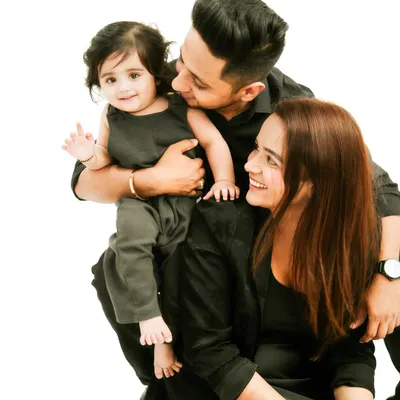 A beautiful family portrait. Coordinating in black outfits, this family of three shares a moment of love and happiness. The baby's wave is a perfect touch.