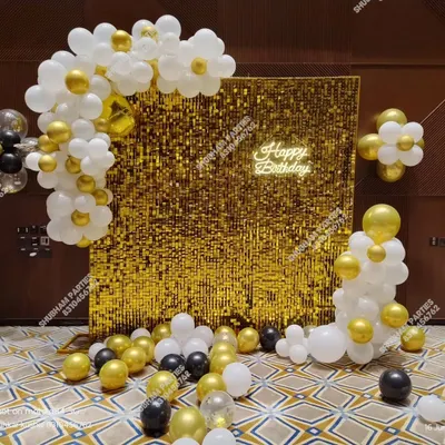 A stunning gold sequin wall backdrop, perfect for adding glamour to any birthday party. This setup includes a white and gold balloon garland and a "Happy Birthday" neon sign.