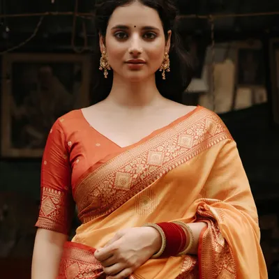 A portrait that captures timeless grace. The model, draped in a beautiful Banarasi saree, looks on with a serene expression, her elegance enhanced by the rustic market setting.