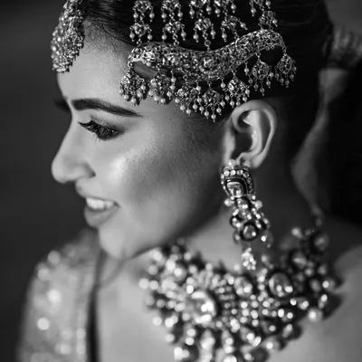 A timeless black and white close-up of the bride, highlighting her intricate jewelry and joyful smile. This classic style emphasizes emotion and detail.