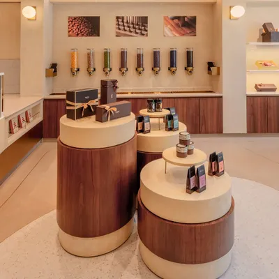 The central display pods at Entisi were custom-designed to be movable, allowing for flexible merchandising of seasonal products. Their tiered, cylindrical form, combining wood and a terrazzo-like finish, creates a focal point that draws customers into the heart of the store.