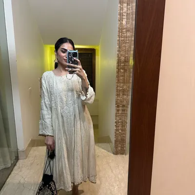 A mirror selfie showing a self-designed off-white anarkali. This is a versatile piece that can be styled for various festive occasions.