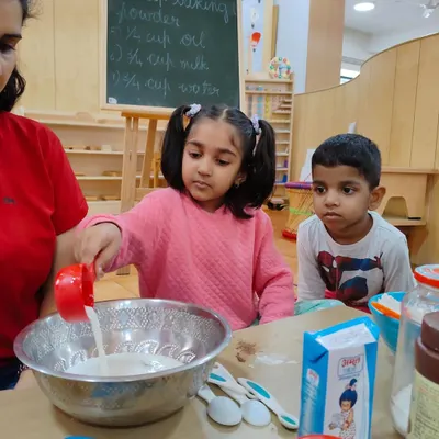 Baking a cake is a lesson in so many things. Here, a child carefully measures milk, learning about quantities and the importance of following a recipe.