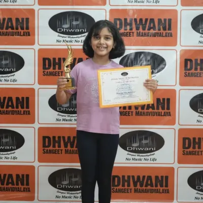 A happy student with her award from the Dhwani Kala Mahotsav. This focus on personal growth is central to our wellness classes for kids and adults.