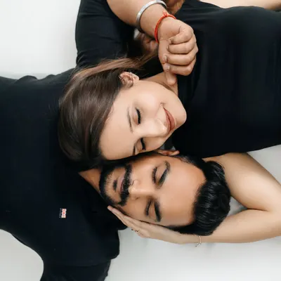 This overhead portrait from a minimalist indoor session highlights the couple's closeness. Shot against a simple white backdrop, the focus is entirely on their serene expressions and intimate connection, creating a timeless and artistic piece of their love story.