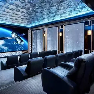A high-end home theater design with a space theme. The room features comfortable black leather recliners, a large projection screen, and a ceiling with a custom-printed galaxy pattern.