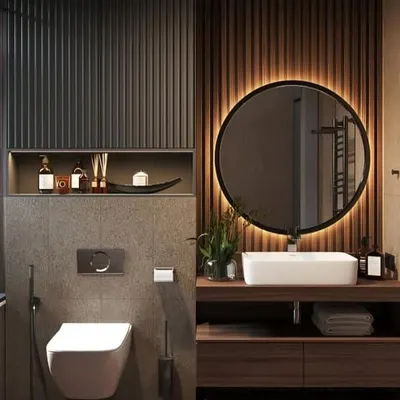 A contemporary bathroom featuring a custom floating wood vanity, a large backlit round mirror, and a mix of dark fluted and wood paneling on the walls.