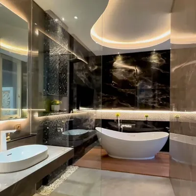 This master bathroom exemplifies our approach to luxury, combining opulent materials with functional design. We used bookmatched black marble slabs to create a dramatic feature wall, complemented by an organic-shaped freestanding tub and subtle cove lighting in the ceiling to create a serene, spa-like atmosphere.