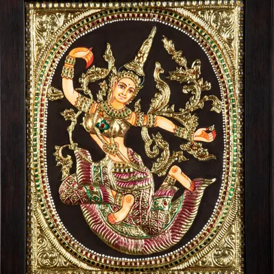 A detailed photograph of a traditional, ornate Tanjore painting depicting a celestial dancer, capturing the gold foil and embedded gems.