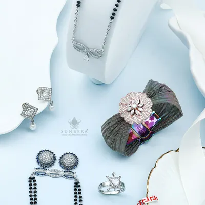 This flat lay composition shows the diversity of our silver jewellery collection. It features a modern mangalsutra, statement earrings, rings, and a unique fabric based brooch, reflecting a blend of traditional concepts with contemporary design.
