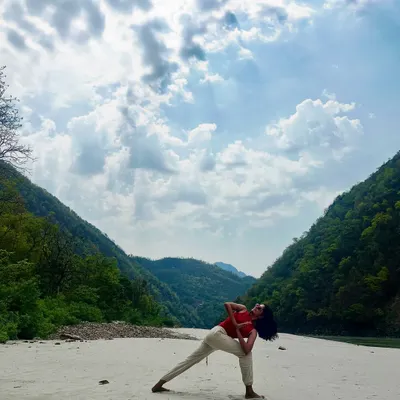 Practicing Parivrtta Parsvakonasana, or Revolved Side Angle Pose, by the Ganga. This twisting pose detoxifies the body and improves spinal mobility, and the natural setting amplifies the feeling of renewal.