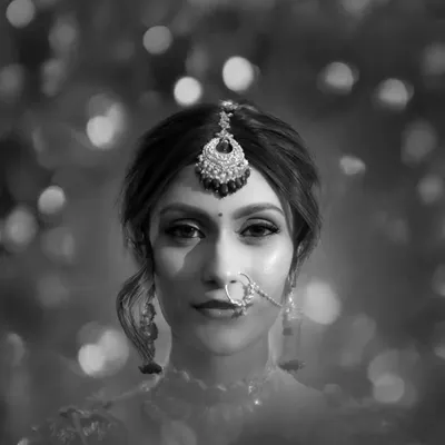A stunning black and white bridal portrait, with a dreamy, bokeh background that makes her expressive eyes and intricate jewelry the focus.