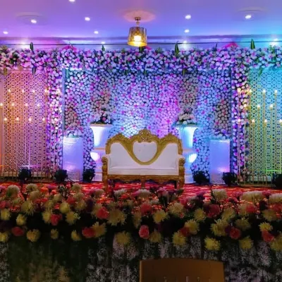 A full-coverage floral wall reception stage, combining thousands of flowers with strategic uplighting to create a breathtaking and luxurious backdrop for the couple.