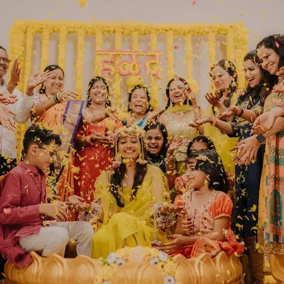 A joyous Haldi celebration! The bride is surrounded by her family as they shower her with flower petals in a moment of pure happiness.