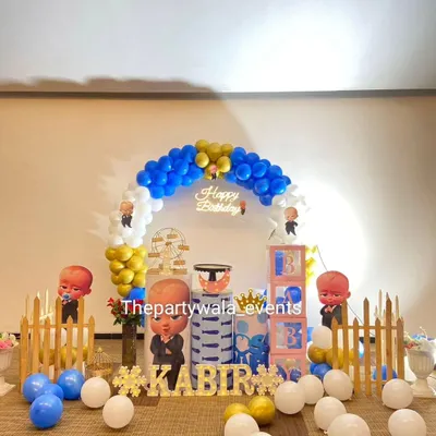 A classic Boss Baby theme for a first birthday. This setup features a 'Happy Birthday' neon sign, character cutouts, and a blue, white, and gold color scheme.