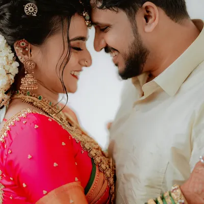 A moment of pure connection, as the bride and groom touch foreheads in a gesture of love and unity. The vibrant colors of their attire and their joyful smiles make this a quintessential wedding portrait.