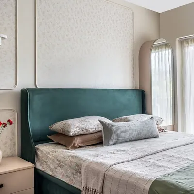 The master suite in 'The Flux Abode' features an emerald green bed set against an ivory wall with floral wallpaper inlays. The design is a perfect blend of contemporary sophistication and subtle luxury.