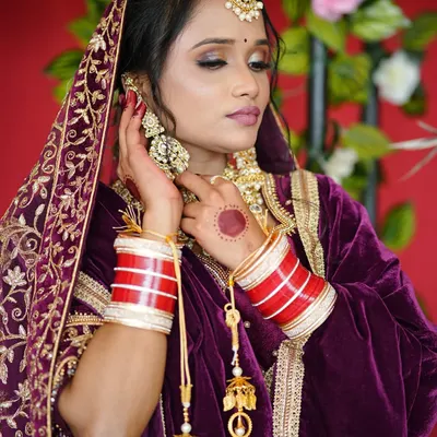 A stunning Punjabi look featuring a rich purple velvet outfit. The makeup includes dramatic smokey eyes and is paired with heavy traditional jewelry.