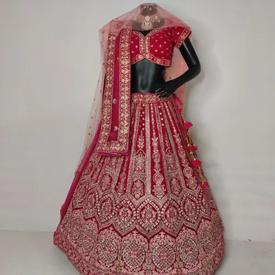 A beautiful red bridal lehenga with pink embroidery displayed on a mannequin. This piece offers a trendy yet elegant look, available for both rent and purchase.